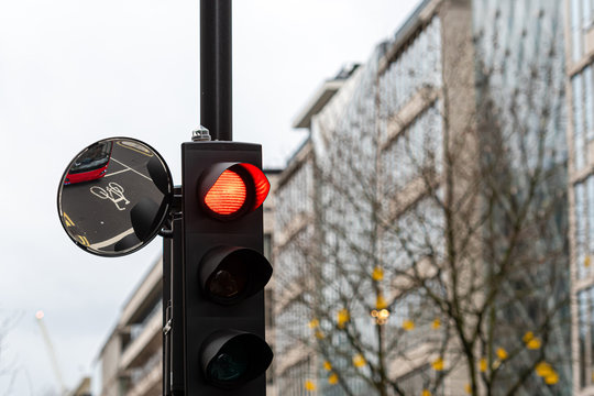 Red Traffic Light Signal And Traffic Convex Mirror With The Reflection Of The Red Bus, London, England, UK