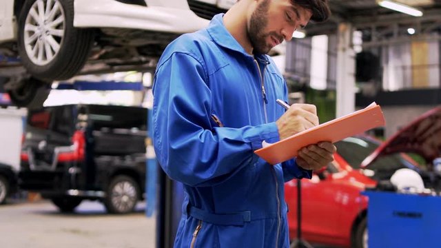 Man specialist an auto mechanic in a car service checks the machine diagnostics check the list of car repairs and lists on the job board.