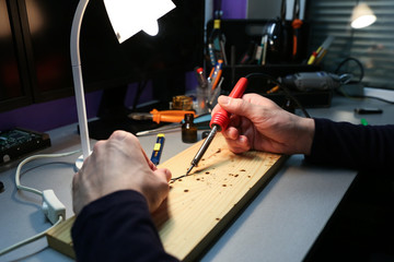  electrician hands are soldering wires in workshop