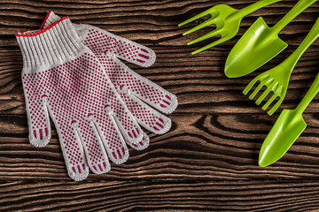 Gardening tools concept. Spade, fork, rake and gloves on wooden background with space for text flat...