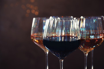 Elegant glasses with different wines on brown background, closeup