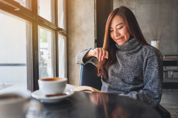 Closeup image of a beautiful woman holding and reading a book with coffee cup on the table