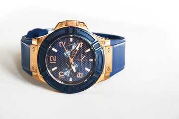 Stylish blue wrist watch on a white background. Round dial in blue and gold colors.
