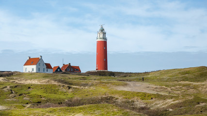 red lighthouse on an island with dunes