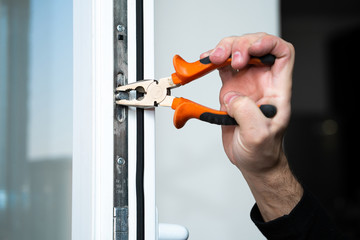 Professional master for repair and installation of windows, sets up a window opening system in winter mode