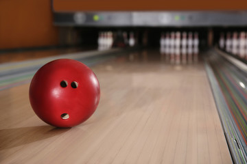 Red ball on bowling lane in club. Space for text
