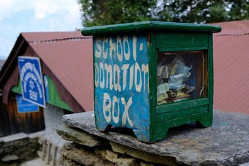 School donation box full of maney next to school in small Nepalese mountain village. During treking...