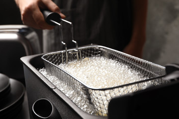 Chef cooking delicious french fries in hot oil, closeup