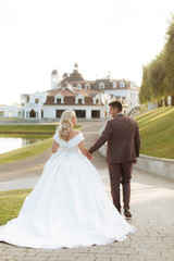 Bride and groom at wedding Day walking Outdoors on spring nature. Bridal couple, Happy Newlywed woman and man embracing in green park. Loving wedding couple outdoor.