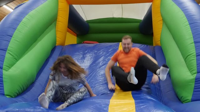 4K: Young People having fun Jumping down an Inflatable / Bouncy Slide indoors - Slow motion. Stock Video Clip Footage