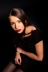 Portrait of a beautiful young woman in a black dress with a cool makeup and good skin. Studio, black background.