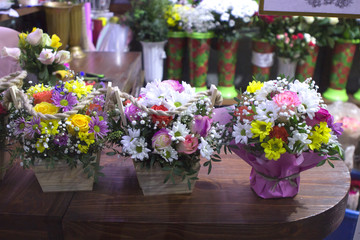 Fototapeta na wymiar bouquets with flowers on the counter of a flower shop. Roses, chrysanthemums and alstroemeria in wooden vase boxes