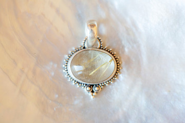 Sterling silver pendant with crystal quartz on white mother pearl background