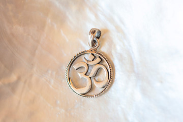 Sterling silver pendant with mandala om symbol on white mother pearl background
