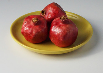 Red pomegranates on a yellow plate