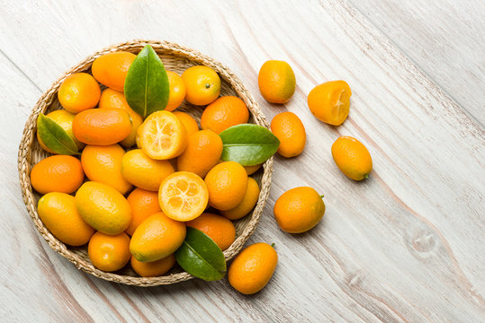 Kumquat fruits into basket on wooden table. © winston