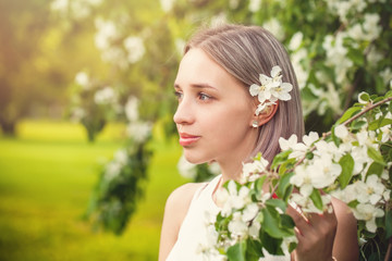 Fototapeta premium Pretty girl in spring flowers garden