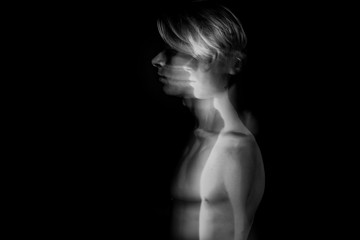Beautiful fuzzy mystical mysterious ambiguous original conceptual profile side portrait of young blonde man on a black background. Black and white photo. long exposure. Artistic concept