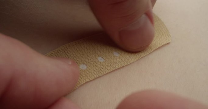 Putting Adhesive Bandage Plaster on a Skin Wound Injury a Macro Shot on Red Camera