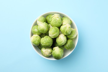 Bowl with brussels sprout on blue background, top view