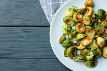 Plate with brussels sprout on wooden background, top view