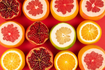 Grapefruit, orange, pomegranate, citrus sweetie on red background.