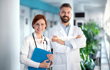 A portrait of man and woman doctor standing in hospital.
