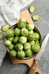 Composition with bowl of brussels sprout on grey background, top view