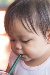 cute little asian girl sucking water from bottles