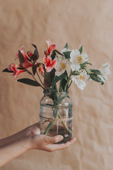 Unrecognizable woman hands holding up a glass jar full with easter eggs. Colorful spring flowers in the glass jar. Spring floral stock image
