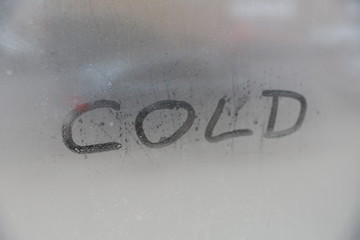 handwritten word cold on misted glass