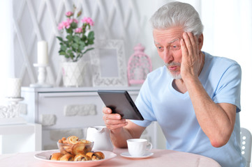 Portrait of senior man reading article from tablet