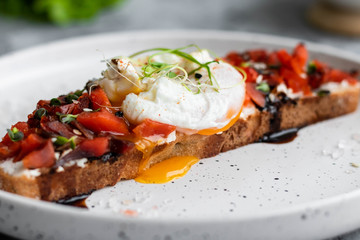 Sandwich with red fish, poached egg, balsamic vinegar and micro-greens
