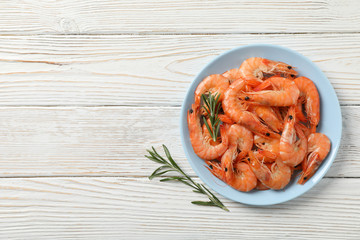 Plate with shrimps on wooden background, top view