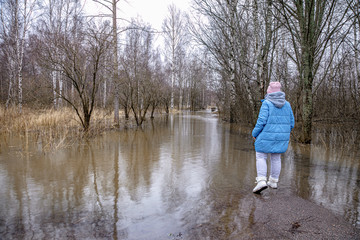 Fototapeta na wymiar Flood. A woman is trying to escape. go through the water. Finland, February 2020