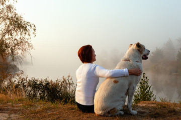 Tourist girl in forest on halt with dog. mistress plays with hunting hound. mistress caresses dog. Happy woman breeder dog walks with dog.