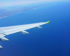 Obraz premium VIew of blue sea from an airplane window. Landscape coast, airplane wing