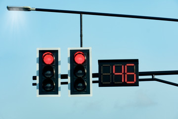 Red traffic lights with countdown numbers under the sky.