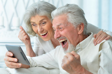 Portrait of happy senior couple using tablet