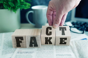 FAKE or FACT on wooden blocks on newspaper, real news or fake news concept