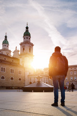 Tourism in Salzburg: Young man is standing on the cathedral square and watching the sundown
