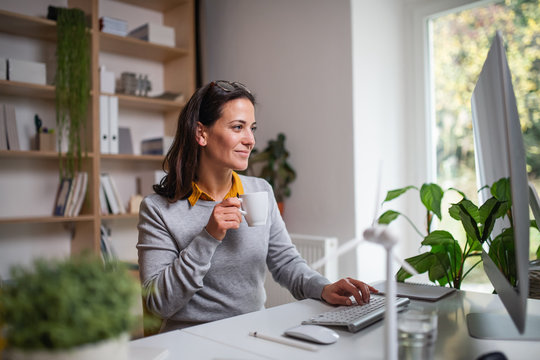 Attractive businesswoman sitting at the desk indoors in office, working.