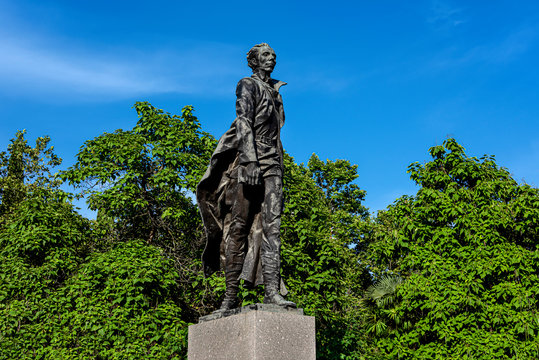 Russia, Black Sea, Sochi: Nikolai Ostrovsky statue monument in a public park in the city center of the Russian town with square, green trees, garden and blue blue sky - literature author culture