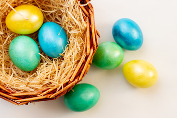 Fototapeta na wymiar multicolored bright easter eggs in a brown basket, top view