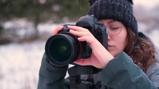On a snowy day, a girl photographer takes pictures of the winter forest. Strong bokeh, the camera moves