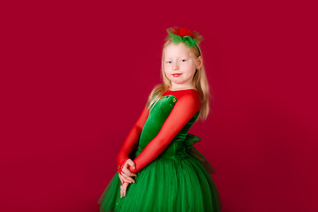 Beautiful little plump girl princess dancing in luxury green dress isolated on red background. Carnival party with costumes
