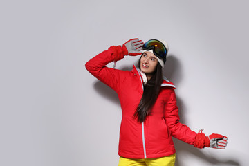 Woman wearing stylish winter sport clothes on light grey background
