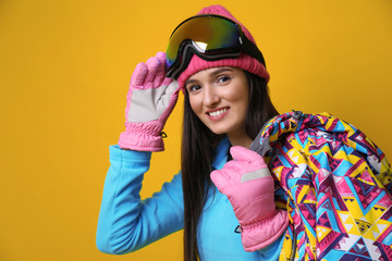 Woman wearing stylish winter sport clothes on yellow background