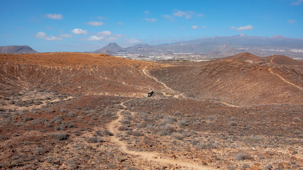 Elevated views of the arid volcanic landscape surrounding the summit of Montana Amarilla towards Pico del Teide and the small terraced villages, in Costa del Silencio, Tenerife, Canary Islands, Spain