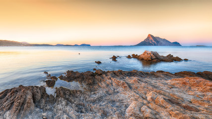 Fantastic sunset time over azure water with rocks near beach Porto Taverna.